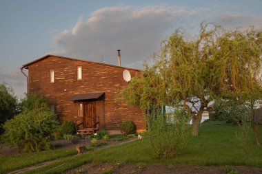 Kırsal kesimde günbatımında bahçeli ahşap bir ev.