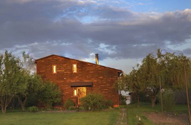 Kırsal kesimde günbatımında bahçeli ahşap bir ev.