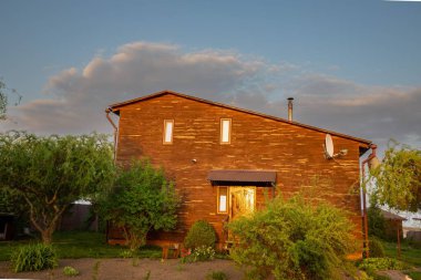 Kırsal kesimde günbatımında bahçeli ahşap bir ev.