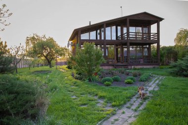 Kırsal kesimde günbatımında bahçeli ahşap bir ev.