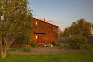 Kırsal kesimde günbatımında bahçeli ahşap bir ev.