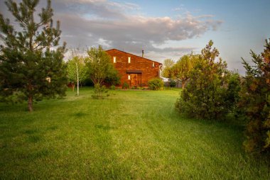 Kırsal kesimde günbatımında bahçeli ahşap bir ev.