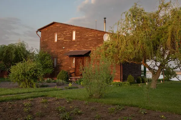 Kırsal kesimde günbatımında bahçeli ahşap bir ev.