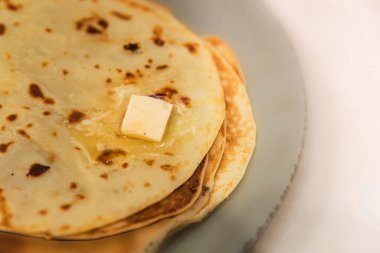 Eriyen tereyağlı krep yığını, yakın çekim yiyecek fotoğrafçılığı.