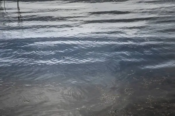 Su yüzeyine düşen yağmur damlaları, dalgalı doku arkaplanı