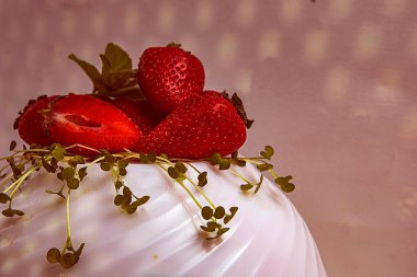 Çilekler ve mikro yeşiller sanatsal ışıkta gölgeler ve yansımalarla