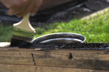 Açık havada siyah boya ile ahşap bir kiriş boyuyorum.