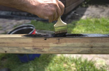 Açık havada siyah boya ile ahşap bir kiriş boyuyorum.