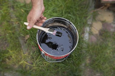 Açık bir teneke üzerinde siyah boyaya batırılmış el fırçası.