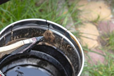 Açık bir teneke üzerinde siyah boyaya batırılmış el fırçası.