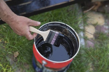 Açık bir teneke üzerinde siyah boyaya batırılmış el fırçası.