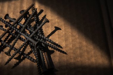 Kartondaki siyah vidaların dramatik ışık ve gölgede sanatsal düzenlemesi