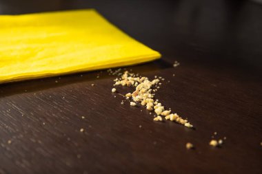 Sarı temizlik bezi ve yemek kırıntıları koyu ahşap masa, ev temizliği konsepti.