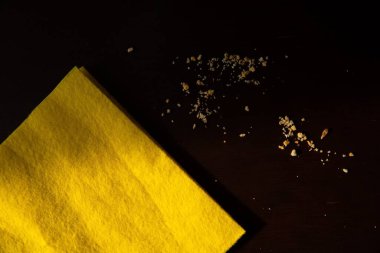 Sarı temizlik bezi ve yemek kırıntıları koyu ahşap masa, ev temizliği konsepti.