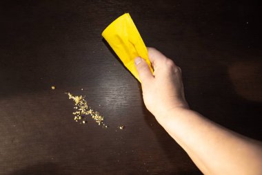 Koyu renk masa kırıntıları, sarı bez, ev hijyeni kavramı.