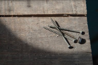 Güneş ışığı, inşaat ve onarım konseptinde karton yüzeyde siyah vidalar yığını