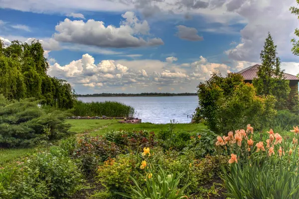 Çiçekler açan ve mavi gökyüzünün altında göl manzaralı kırsal alan.