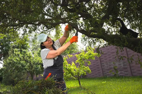 Güçlü bağımsız kadın bahçede çalışıyor ve yeşil atıkları temizliyor.