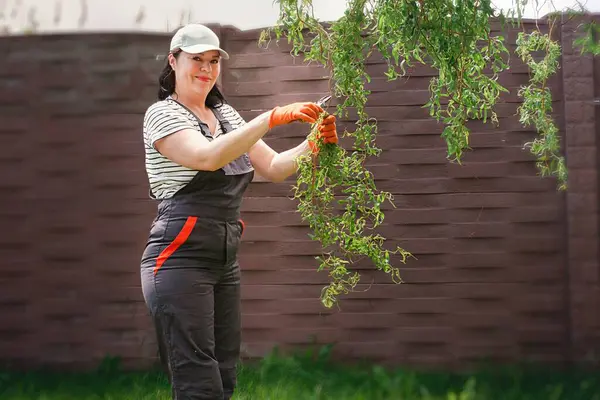 Güçlü bağımsız kadın bahçede çalışıyor ve yeşil atıkları temizliyor.