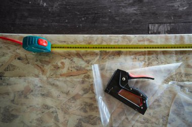 OSB panelinde plastik kaplamalı zımba ve mezura.