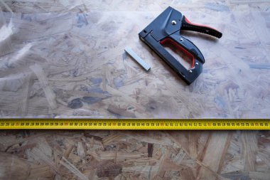 OSB panelinde plastik kaplamalı zımba ve mezura.