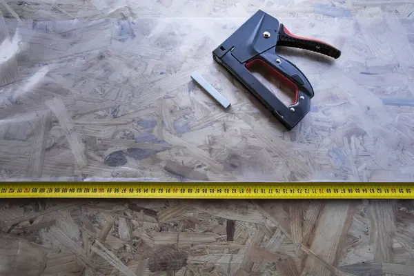 OSB panelinde plastik kaplamalı zımba ve mezura.