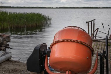 Göl kıyısında beton karıştırıcı. Kırık rıhtım ve sazlıklar var. Endüstri ve doğanın aksine.