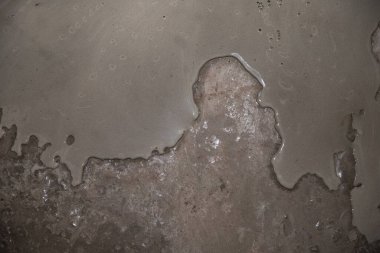 Parlak yüzeyi ve pürüzlü yapısı olan nemli beton dokusu, inşaat malzemesi arka planı