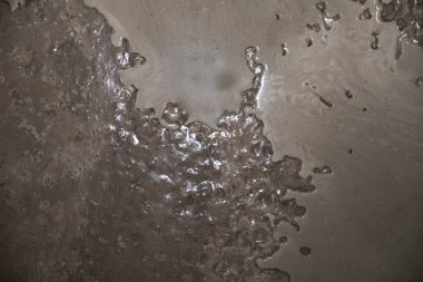 Parlak yüzeyi ve pürüzlü yapısı olan nemli beton dokusu, inşaat malzemesi arka planı