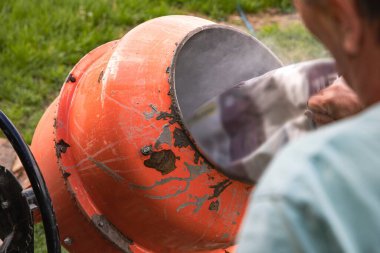 Eski turuncu çimento karıştırıcısında kuru beton ve açık hava inşaat malzemeleri var.