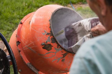 Eski turuncu çimento karıştırıcısında kuru beton ve açık hava inşaat malzemeleri var.