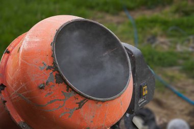 Eski turuncu çimento karıştırıcısında kuru beton ve açık hava inşaat malzemeleri var.