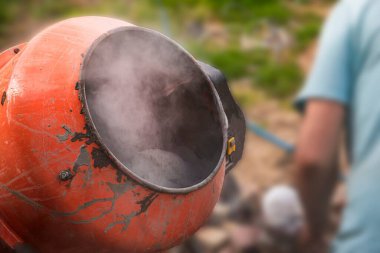 Eski turuncu çimento karıştırıcısında kuru beton ve açık hava inşaat malzemeleri var.