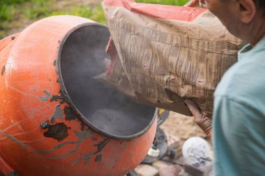 İnşaat sırasında beton karıştırıcıya kuru çimento dökülüyor.