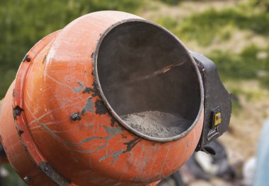 Eski turuncu çimento karıştırıcısında kuru beton ve açık hava inşaat malzemeleri var.