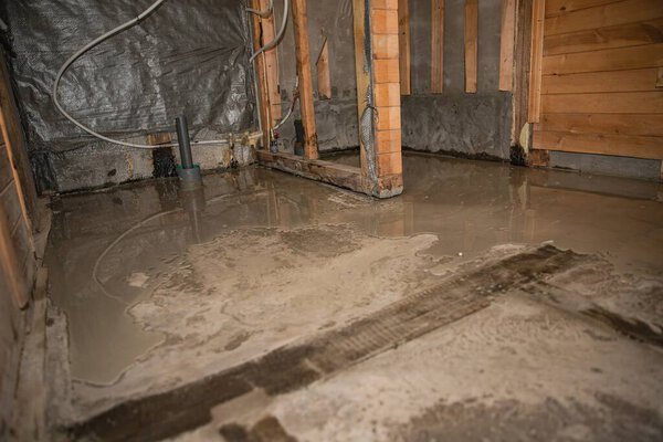 Влажный бетонный пол свежевылитый внутри деревянного здания в процессе ремонта