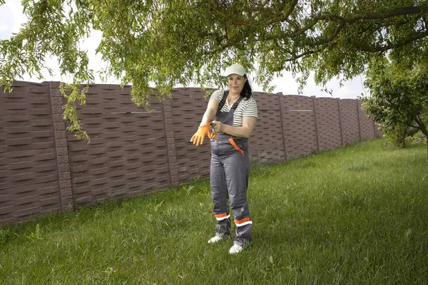 Arka bahçede ağaç dallarını budayan bir kadın.