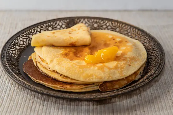 Üstünde tereyağı eriyen sıcak altın krepler. Eski tarz tabakta servis edilen ev yapımı yemekler. Kahvaltı, rahat mutfak sahneleri ve mutfak temaları için mükemmel..