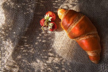 Yakın plan kruvasan ve nane yapraklı çilek. Yumuşak gün ışığıyla vurgulanmış. Yemek tasarımı ve makro aşıklar için mükemmel..
