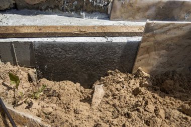 İnşaat alanındaki temel çalışması ve su geçirmez beton duvar. Kum ve inşaat malzemeleri görünür.