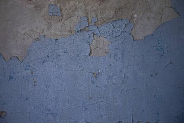 Çatlak kil duvardaki mavi boyayı soyuyordu. Terk edilmiş binanın Grunge dokusu tasarım, arkaplan ve çürüme konsepti için mükemmel..