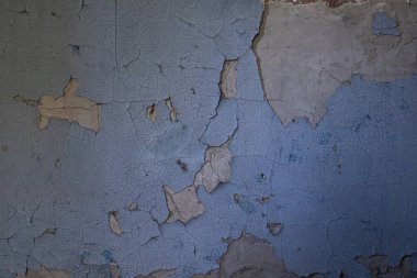 Çatlak kil duvardaki mavi boyayı soyuyordu. Terk edilmiş binanın Grunge dokusu tasarım, arkaplan ve çürüme konsepti için mükemmel..