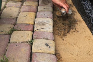 İşçi, su geçirmez temellerin yanındaki kum tabanına elle taş döşüyordu.