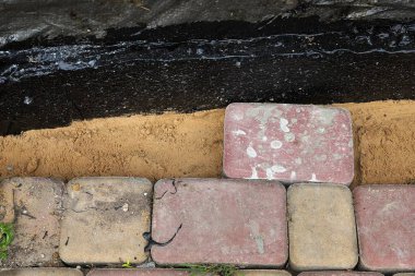 Siyah su geçirmez temellerin yakınındaki kum tabanına taş döşenmiş. Kentsel bahçe inşaatı, patika tesisatı, bina yenileme..