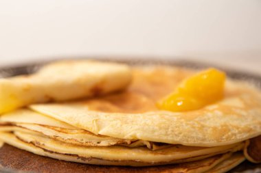 Üstünde kayısı reçeli ve süslü metal bir tabakta servis edilen ince krep yığını. Geleneksel ev yapımı tatlı meyveli kahvaltı..