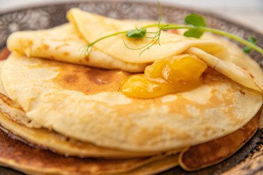 Bir kaşık dolusu kayısı reçelli altın krep detaylarıyla. Yumuşak dokuları ve sıcak tonlarıyla tatlı tatlı konsepti.