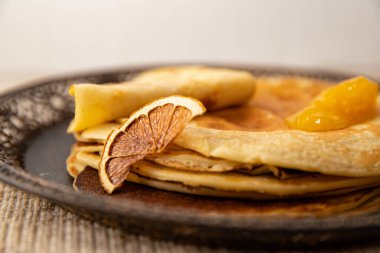 Kurutulmuş portakal dilimi ve altın kayısı reçeli ile servis edilen krep yığını. Zarif kahvaltı mı yoksa kırsal tonda tatlı fikri mi?.