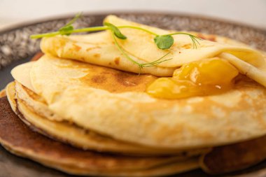 Bir kaşık dolusu kayısı reçelli altın krep detaylarıyla. Yumuşak dokuları ve sıcak tonlarıyla tatlı tatlı konsepti.