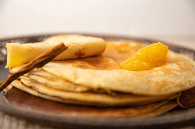 İngilizce: Üzerinde altın bal ve tarçın bulunan ev yapımı krep yığınının yakın çekimi. Sıcak ve tatlı kahvaltı fikri.