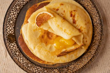 Kurutulmuş portakal dilimi ve altın kayısı reçeli ile servis edilen krep yığını. Zarif kahvaltı mı yoksa kırsal tonda tatlı fikri mi?.